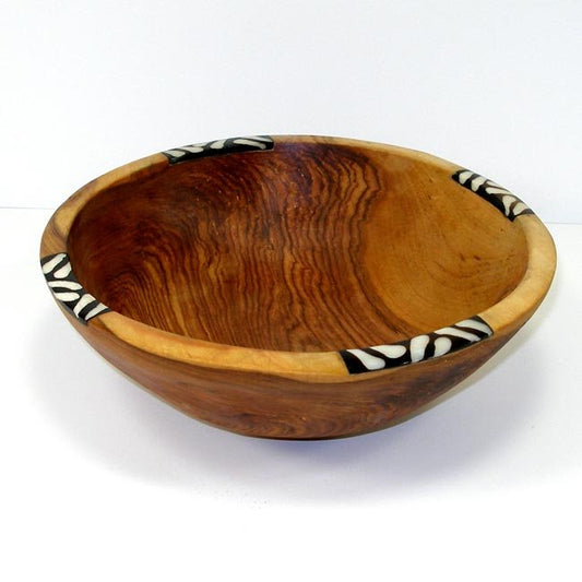 This highly grained olive wood bowl is hand-carved in Kenya using rudimentary hand tools. In a gorgeous color, this bowl also features inlaid piece of discarded cow bone, batiked in a mudcloth pattern using traditional dye methods. Size 10 inches.